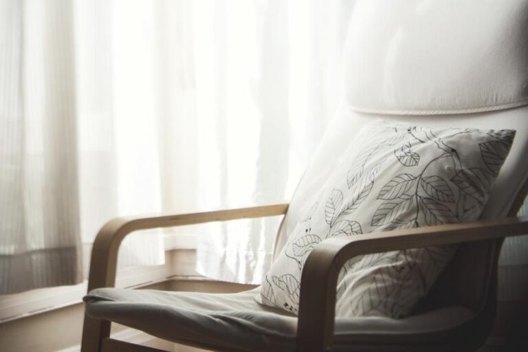 An empty armchair with a cushion beside a sunlit window