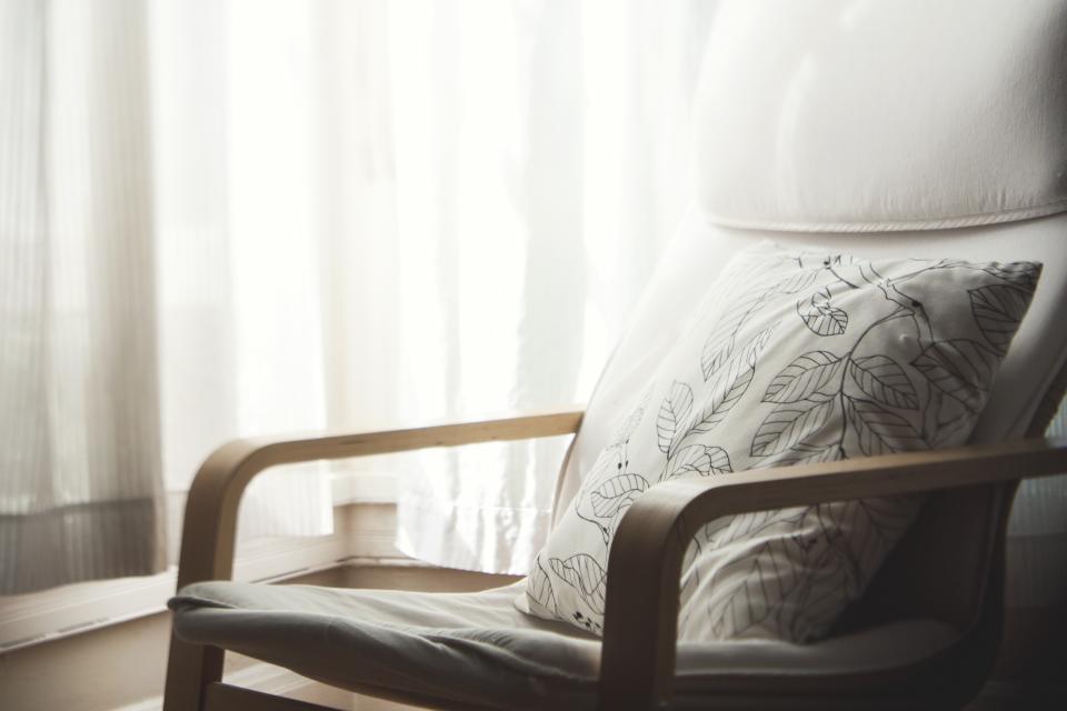An empty armchair with a cushion beside a sunlit window