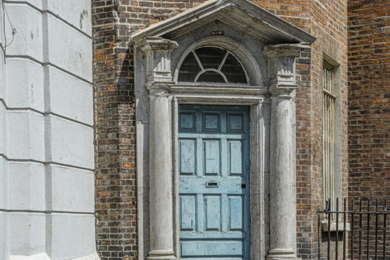 A weathered blue Georgian doorway set in a brick wall