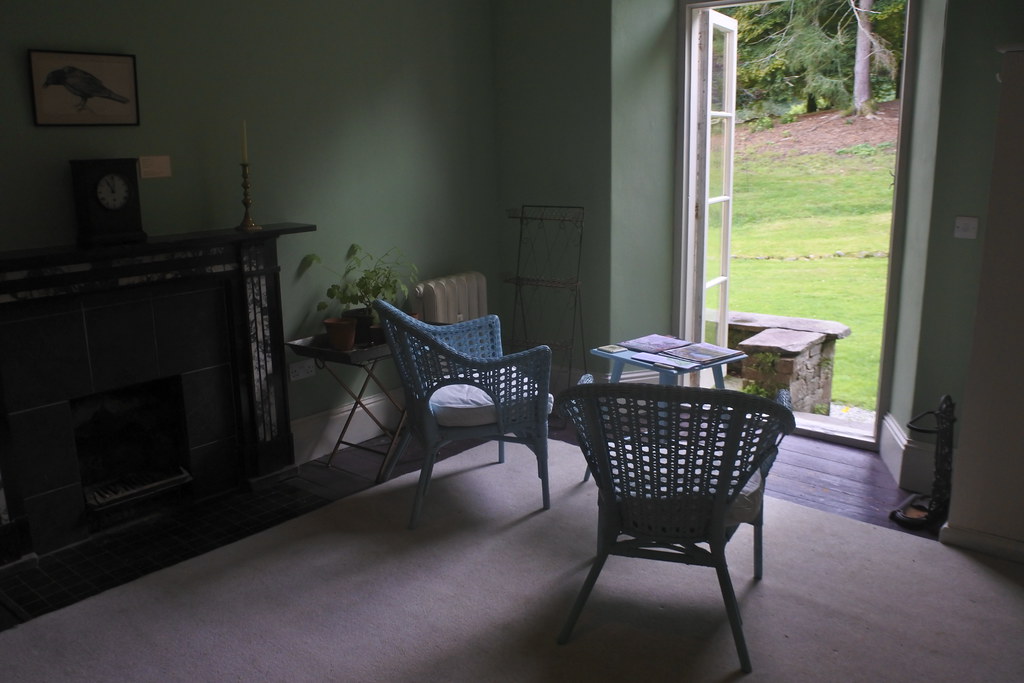 Two wicker chairs in a quiet room beside an open door onto a garden