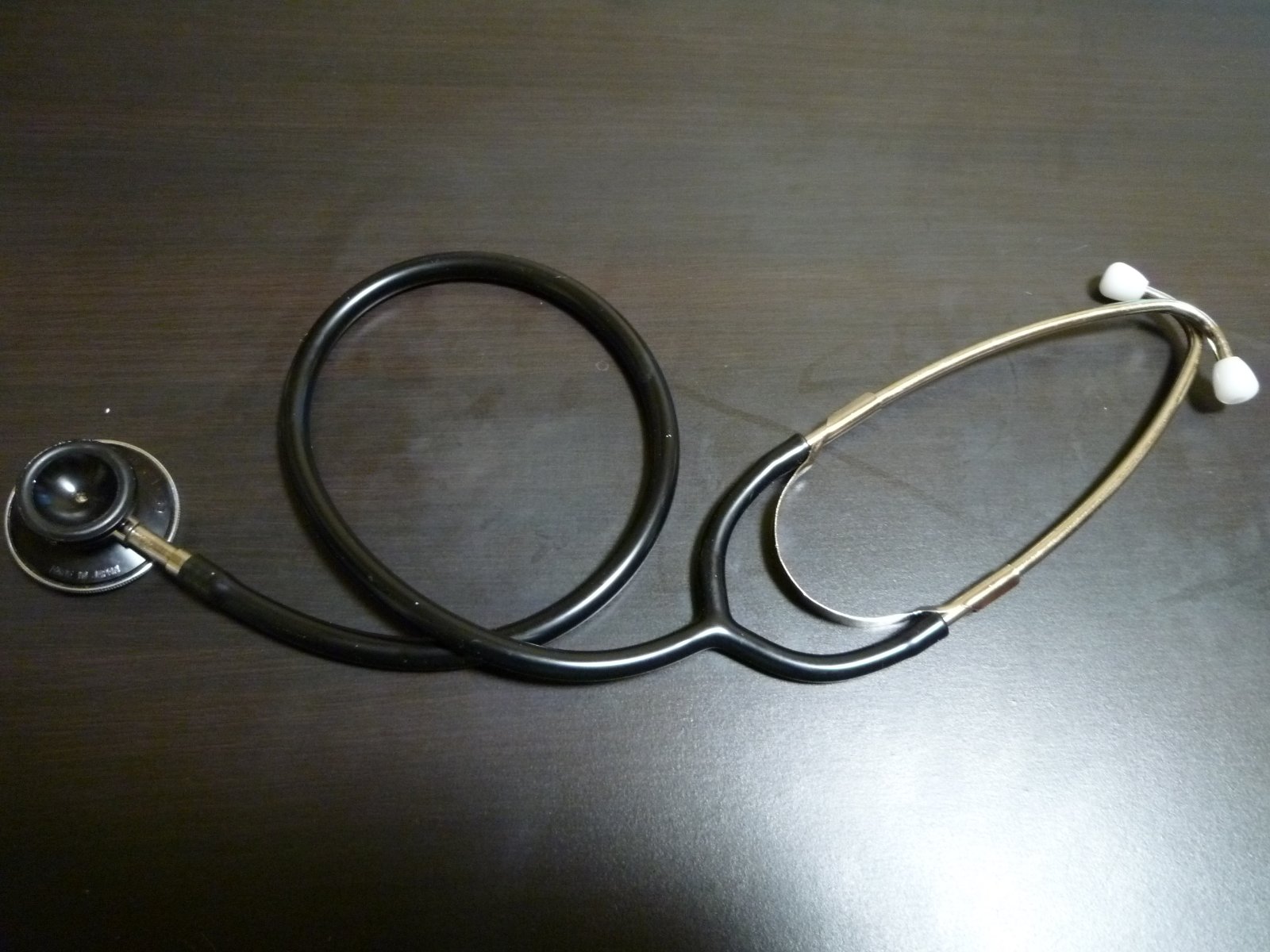 A stethoscope lying on a dark wooden table