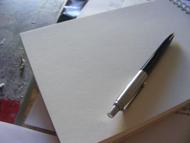 A pen resting on a blank notebook